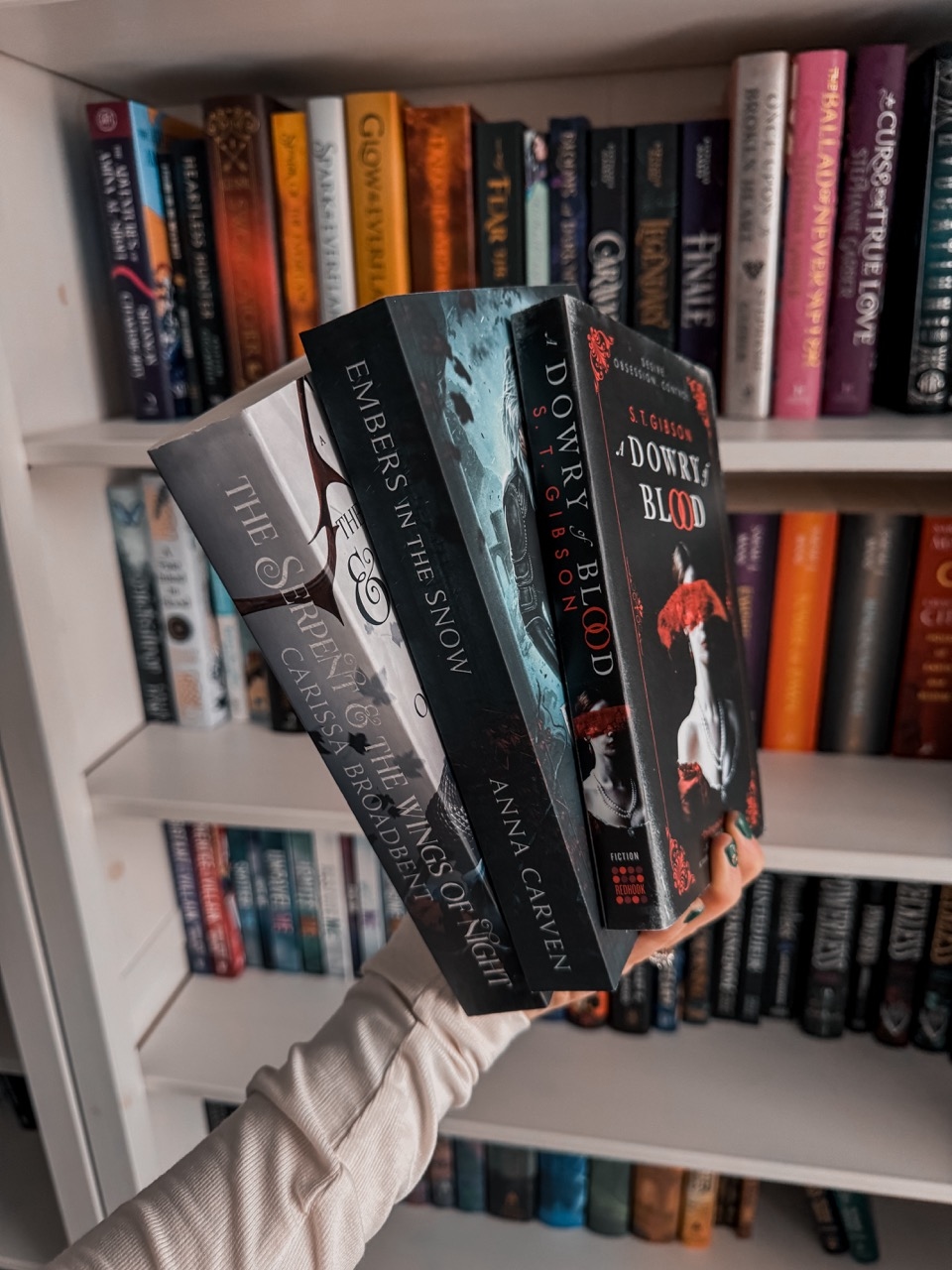 three vampire romantasy books in front of a bookshelf