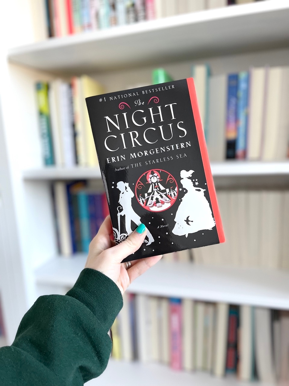 Front cover of the fantasy novel The Night Circus by Erin Morgenstern in front of a bookcase